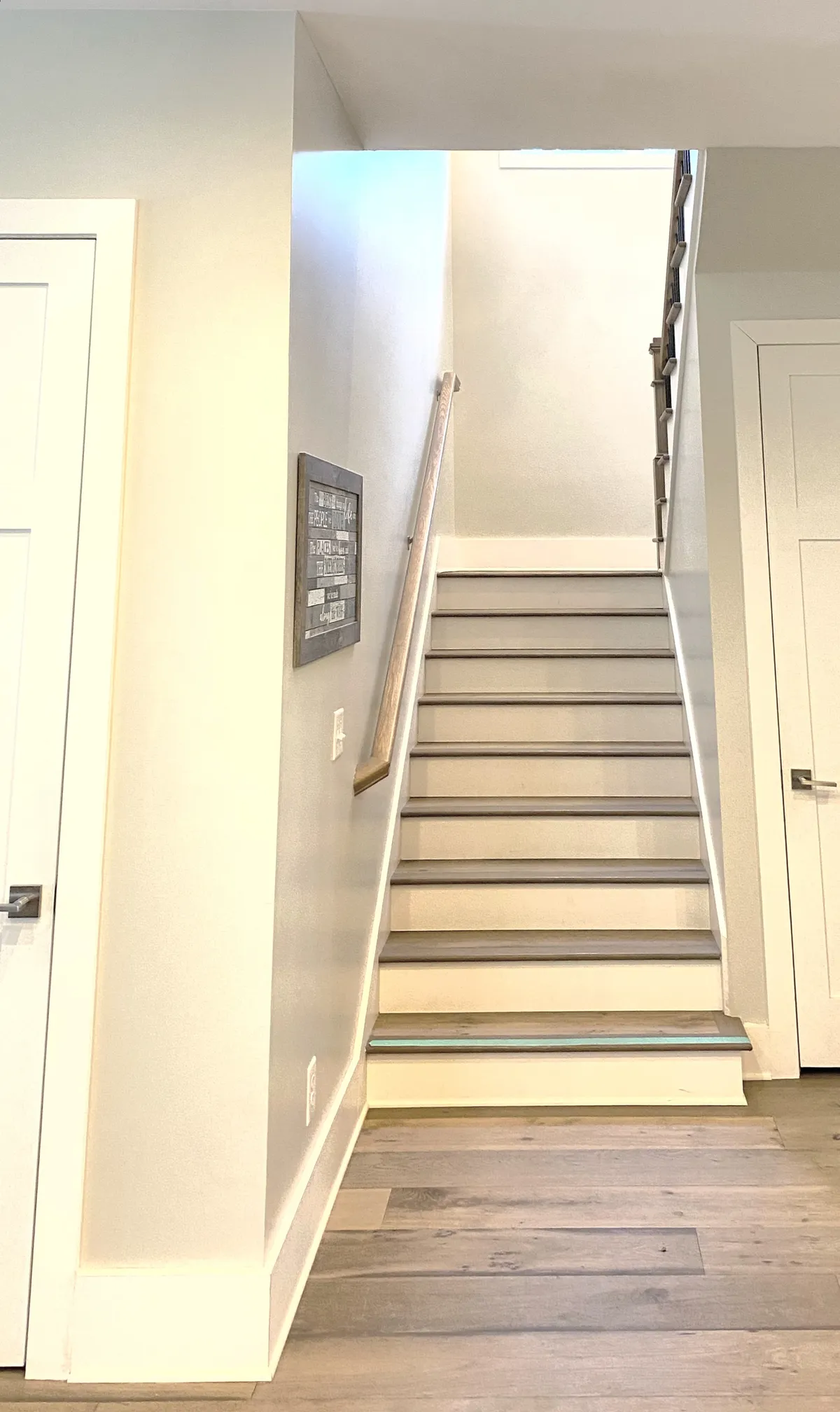 This image features a stylish staircase with a handrail and artistic wall decor, offering a sense of movement and transition within the home. The inviting atmosphere hints at the home's spacious layout and the journey between shared and private spaces.